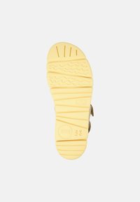 Gelbe Gummisandalen-Sohle mit strukturierten Rillen für Grip, gekennzeichnet mit Markenlogo und Größe 38. Flaches und breites Design für Komfort.