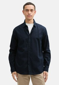 Marineblauw overhemd met knopen en een klassieke kraag, lange mouwen en een soepele textuur. Gemaakt van lichtgewicht stof met een casual pasvorm.