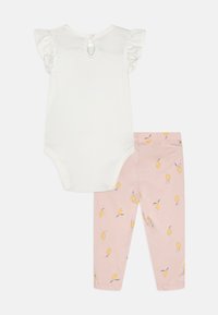 Body bianco con maniche arricciate e bottone sul retro, abbinato a leggings rosa con un motivo di limoni e polsini alla caviglia.