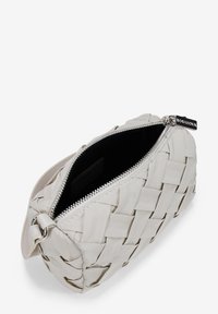 Bolsa de aseo de piel blanca tejida con cierre de cremallera, forro interior negro y herrajes plateados en la cremallera. Forma rectangular compacta.