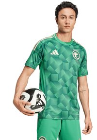 Maglia da calcio verde con motivi geometrici, maniche corte e collo tondo; abbinata a pantaloni corti coordinati e un pallone da calcio bianco e nero.