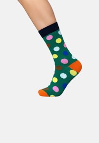 Grøn bomuldsok med multicolore prikker, marineblå kant og orange hæl- og tådetaljer. Glat tekstur, design i midtlængde.