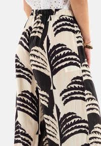 Pantalones de pierna ancha con estampado en tejido ligero, que presentan un diseño de hojas de palma en negro y crema, con una cinturilla elástica para mayor comodidad.