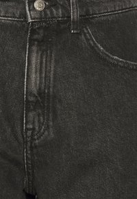 Svarta jeans i denim med högmidjad design, utrustade med fem fickor, en metallknapp och en subtil lyster i tygstrukturen.