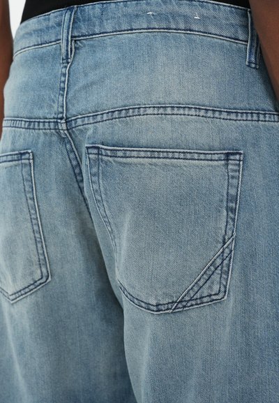 Ljusblå denimjeans med en lätt blekt yta, som har två bakfickor och synliga sömnadsdetaljer.