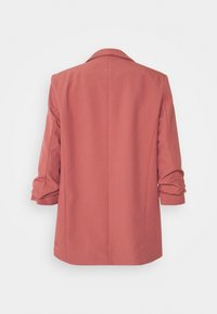 Blazer oversize rosa con colletto a revers e maniche arrotolate, caratterizzato da una texture liscia e una silhouette strutturata, senza chiusure visibili.