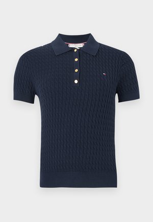 Marineblå kortærmet strikket poloshirt med kabelstruktur, ribkantede manchetter, gyldne knapper og lille rød, hvid og blå logo på brystet.