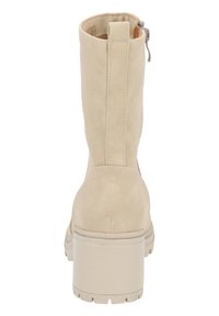 Beżowe zamszowe botki za kostkę na słupku, z bocznym zamkiem błyskawicznym i tłoczonym logo. Gładka faktura z wzmocnionym szwem.