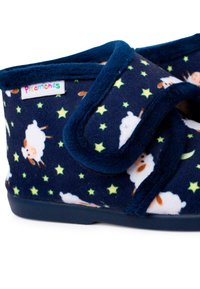 Chaussons en polaire marine ornés de motifs de moutons et d'étoiles, avec une texture douce, des bandes Velcro et des semelles en caoutchouc durables pour la stabilité.