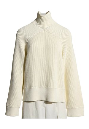 Pull en maille côtelée de couleur crème avec col montant, manches longues et larges poignets présenté sur fond blanc.