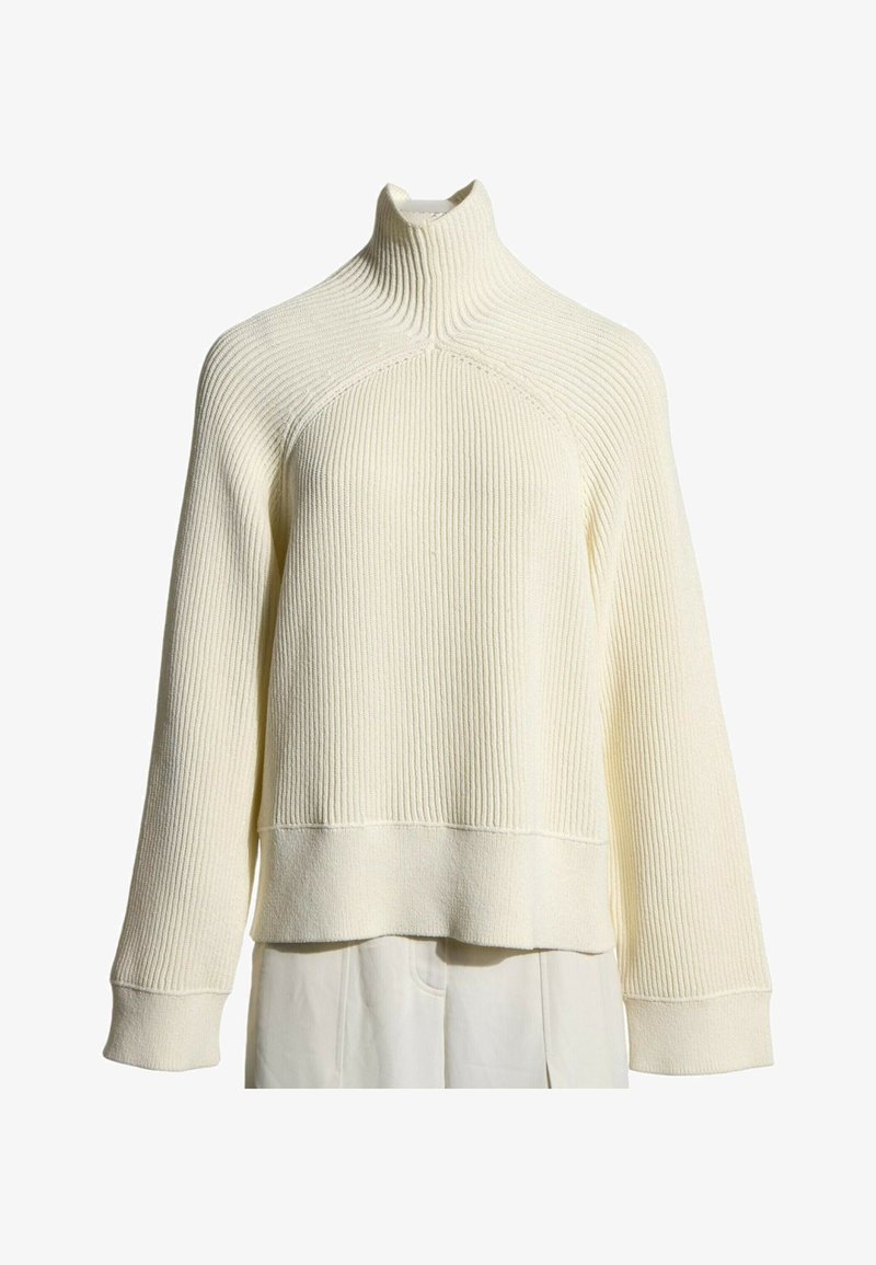 Pull en maille côtelée de couleur crème avec col montant, manches longues et larges poignets présenté sur fond blanc.