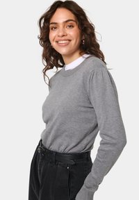 Grauer Pullover mit geripptem Ausschnitt und Bündchen, mit gepufften Ärmeln und weicher Textur. Trägt man über einem weißen Hemd mit Kragen.