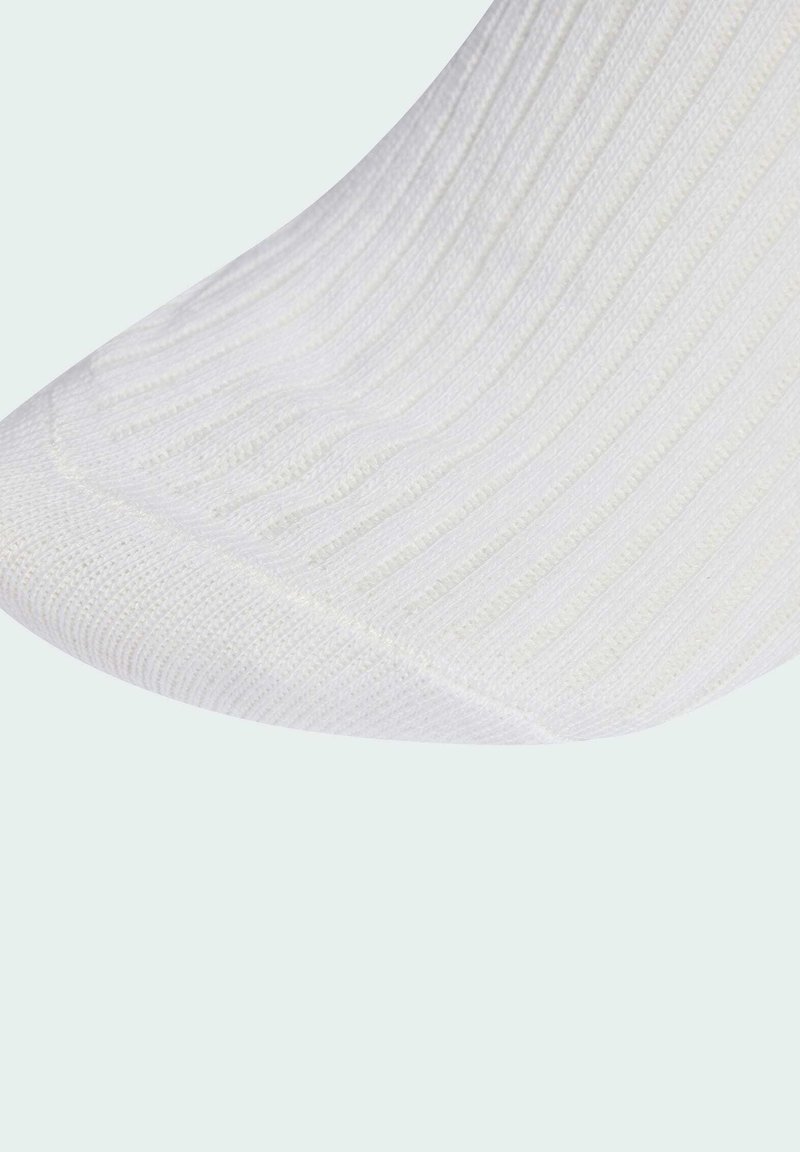 Calza bianca a coste con una superficie liscia e una punta rinforzata. Il tessuto è leggero e si allunga per adattarsi, presentando sottili righe verticali.