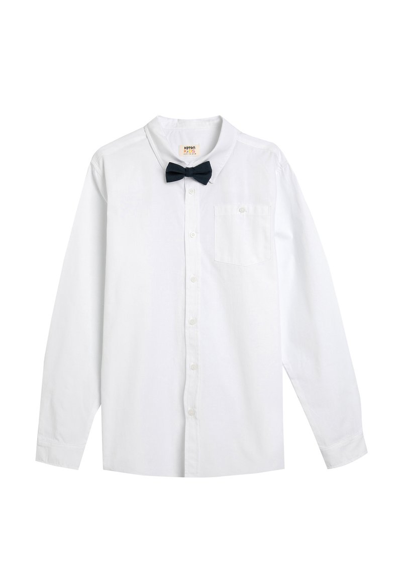 Camisa blanca de manga larga con botones y cuello puntiagudo, acompañada de una pajarita negra. Presenta un bolsillo en el pecho y una textura suave y delicada.