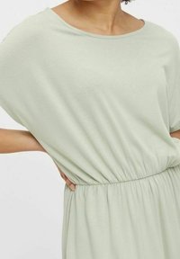 Světlě zelené šaty s volným střihem, kulatým výstřihem a elastickým pasem. Měkká, lehká tkanina s jemnou texturou.
