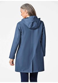 Waterdichte, met capuchon beklede jas in een effen donkere blauwe kleur. Heeft lange mouwen en een rechte snit met een rugopening voor bewegingsgemak.