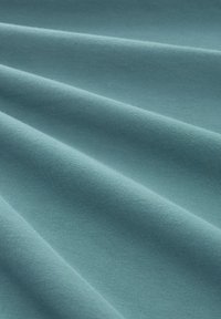 Teal stof med en glat tekstur, der har vandrette folder og et ensartet udseende. Letvægts- og let strækbart materiale.