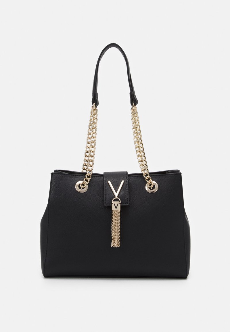 Black synthetic handbag with gold chain handles, featuring a V-shaped accent and a tassel detail. Smooth texture and structured shape.