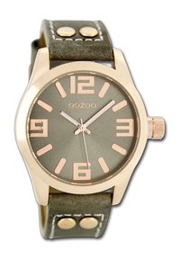 Montre avec bracelet en cuir vert et boîtier en or rose, affichage rond, grands chiffres arabes et aiguilles argentées. Deux accents métalliques sur le bracelet.