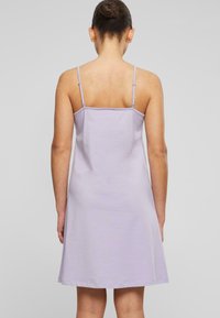 Robe sans manches lilas avec bretelles spaghetti réglables, ourlet légèrement évasé et tissu en coton doux. La vue arrière met en avant le design simple.