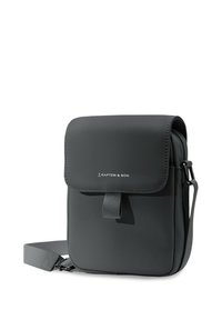 Grå crossbody-väska i syntetmaterial, med klaffstängning, justerbar rem och diskret varumärke på framsidan.