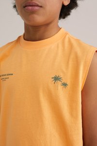 Bezrukávové oranžové bavlnené tričko s grafickým motívom zelenej palma na ľavej hrudi. Mäkká textúra s uvoľneným strihom a čistým výstrihom.
