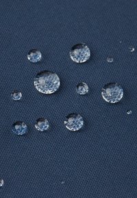 Blå texturerad tyg med flera klara vattendroppar i olika storlekar som vilar på ytan. Dropparna har reflekterande ytor.