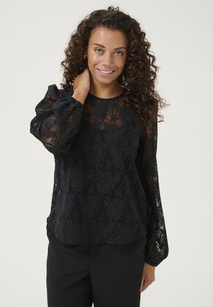 Black lace blouse with a floral pattern, long puffed sleeves, and a rounded neckline, paired with black trousers. Textured sheer fabric.