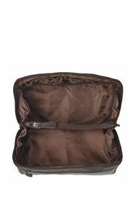 Interno di una borsa in pelle marrone con una texture liscia e lucida. Una tasca con zip, fodera in morbido tessuto e bordi arricciati lungo l'apertura.
