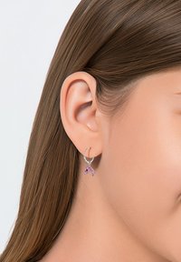 Zilveren hangoorbel met een hangende roze edelsteen in de vorm van de letter "A." Het ontwerp is simpel met een glanzende afwerking en duidelijke details op de stenen.