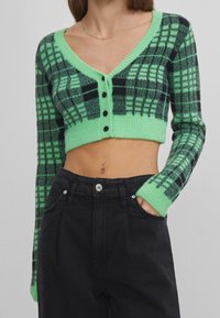 Zielono-czarny kraciasty krótki kardigan z dekoltem w serek, długimi rękawami i pięcioma czarnymi guzikami z przodu. Miękki, teksturowany materiał.