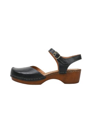 Sandalia zueco de cuero negro con tacón plataforma de madera y correa ajustable en el tobillo con hebilla de metal, vista lateral sobre fondo blanco.