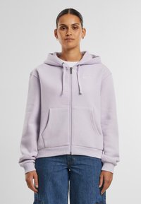 Felpa con zip di colore viola chiaro realizzata in tessuto morbido. Presenta una tasca frontale, cappuccio regolabile con cordini e un semplice logo ricamato sul petto.