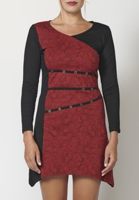 Robe noire à manches longues avec un devant à motif floral rouge, présentant des couleurs contrastées, une coupe ajustée et des accents décoratifs en métal argenté.