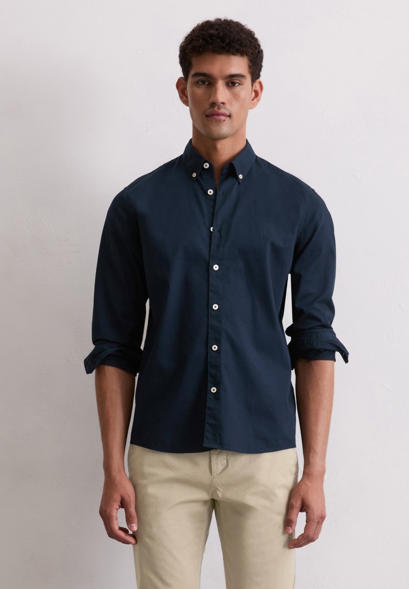 Navyblauwe overhemddie van katoen is gemaakt, met een kraag, opgerolde mouwen en witte knopen. Het shirt heeft een geborduurd logo op de borst.
