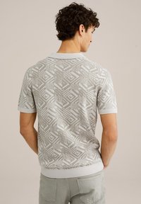 Poloko s krátkymi rukávmi v svetlošedej farbe s geometrickým vzorom. Má rebrovaný golier a lem, vyrobené z jemného pleteného materiálu.