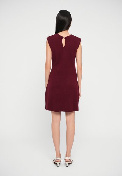 Burgundy knit dress with cap sleeves, knee-length, and a keyhole back detail. Paired with light-colored heeled sandals.