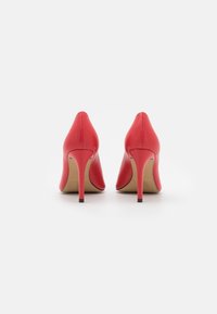 Escarpins en cuir rouge avec un bout pointu et un talon aiguille fin. Texture lisse, détails minimalistes et design uni.