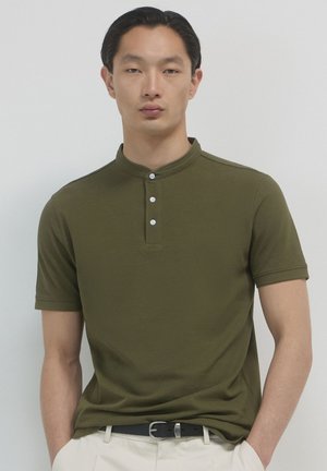 Polo shirt verde oliva a maniche corte con colletto alto e quattro bottoni bianchi. Tessuto morbido e texturizzato con un design aderente.