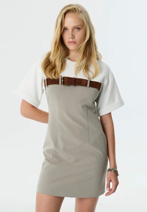 Grijs kledingstuk met een aansluitend lijfje, korte witte mouwen, en een bruine riem om de taille. Glad materiaal met minimale details en naden.