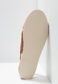 Espadrille marron avec des détails en jute tressé, semelle en caoutchouc avec logo en relief, et accents en tissu colorés sur les côtés.