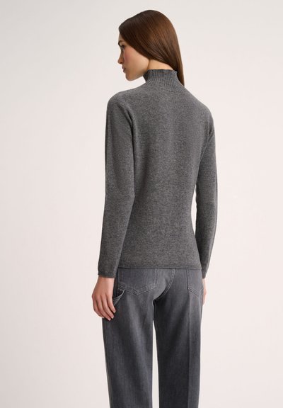 Grauer Rollkragenpullover aus einem weichen, strukturierten Strick, mit einer schmalen Silhouette und langen Ärmeln, kombiniert mit grauen, hochgeschnittenen Jeans.