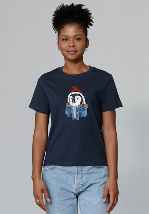 T-shirt en coton bleu marine avec un graphique de pingouin portant une veste bleue et un chapeau rouge avec des pompons, à manches courtes et encolure ronde.