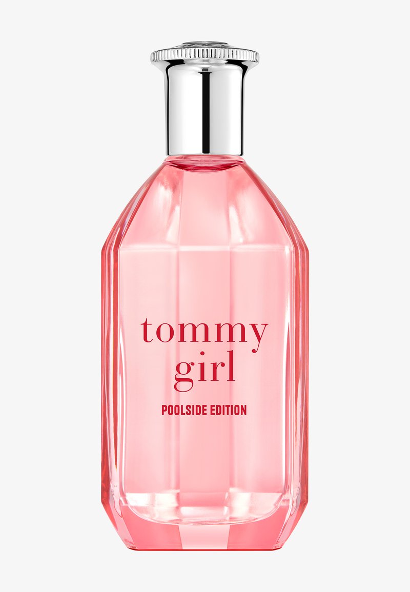 Transparante roze geometrische parfumfles met zilveren dop, gelabeld "tommy girl POOLSIDE EDITION" op een witte achtergrond.