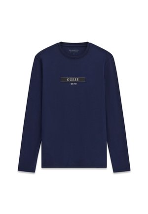 Mörkblå långärmad skjorta i bomull med en svart rektangulär logotypmärke med texten "GUESS EST.1991" i vitt och subtila sömnadsdetaljer.