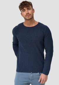 Tummansininen pitkähihaisen villapaidan, jossa on pyöreä kaula-aukko, teksturoitu kangas ja slim fit -leikkaus. Paita sisältää ribbireunat helmassa ja hihoissa.