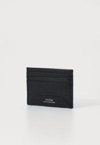 Mustast nahast kaarditasku tekstuuriga viimistlusega, millel on mitmed kaardipesad ja esipaneelil logot tähistav silt "GUESS GENUINE LEATHER."