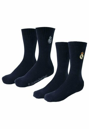 Dwie pary czarnych skarpetek za kostkę, każda z innym białym i złotym logo Realu Madryt wyhaftowanym niedaleko ściągacza.