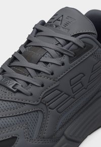 Σκουρόγρινο αθλητικό παπούτσι EA7 Emporio Armani με υφασμάτινη υφή, συνθετικές επικαλύψεις και κορδόνια που διασταυρώνονται.