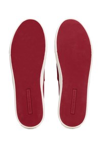 Punainen kumipohja, jossa on teksturoitu pito, valkoisella reunalla. Keskellä logo suorakaiteen muotoisella paikkalla lähellä kantapäätä.